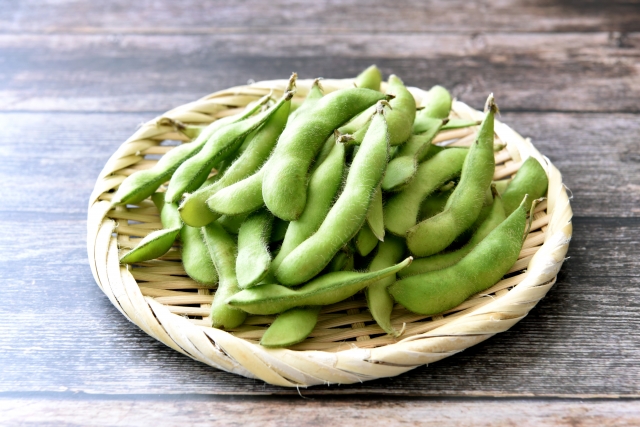 ざるに入った生の枝豆。新鮮な緑色のさやが並び、茹でる前の下ごしらえの様子が伝わる写真