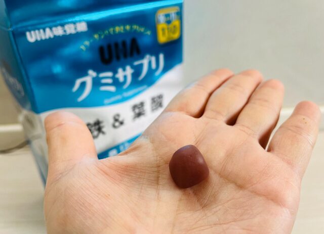 コストコのUHA味覚糖 グミサプリ 鉄&葉酸を1粒、手のひらにのせて畳の上で撮影した写真。粒のサイズ感がわかる自然な使用シーン