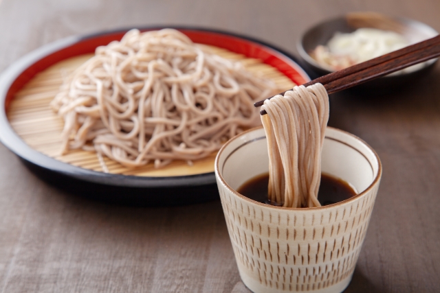 コストコのおびなた戸隠そばとそばつゆを盛り付け、そばを箸で持ち上げている様子。風味豊かなそばの食感が伝わる一場面【商品番号562294】」