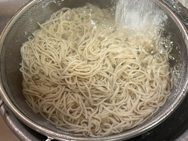 コストコのおびなた 戸隠そばを流水で丁寧に洗っている様子。そばのぬめりを取り、風味と食感を引き立てる工程【商品番号562294】」