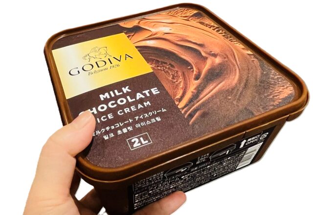 コストコで販売中のGODIVAミルクチョコレートアイスクリーム2Lを手に取る様子。濃厚でなめらかな贅沢チョコレートアイス、大容量でファミリーにも人気【商品番号72215】」