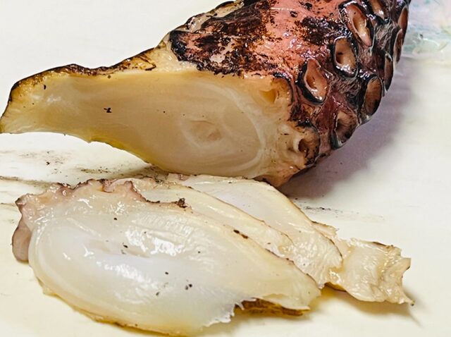 「コストコの炙り北海タコを包丁で薄くスライスした断面。白身と赤い外皮のコントラストが美しい海鮮素材