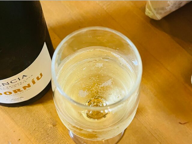 コストコ「コドルニウ エレンシア ブリュット」ITEM#27405。冷えたスパークリングワインをグラスに注ぎ、上から撮影した写真。きめ細かい泡が広がる美しい表面と黄金色の輝きが際立つ、スペイン産カヴァの上品なブリュット。