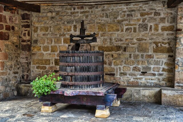 伝統的な木製のワインプレス機。ぶどうを圧搾して果汁を抽出する木の樽型の圧搾機で、ワイン醸造の工程に使用される。クラシックで温かみのあるデザインが特徴のワイナリー設備。