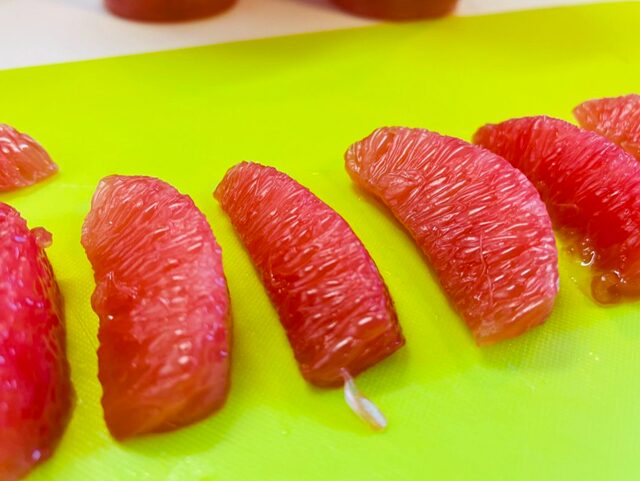 KIRKLAND SIGNATURE レッドグレープフルーツカップの果実10.5個をまな板の上に並べた写真 ズームアップ 粒粒ジューシーさがはっきりわかる