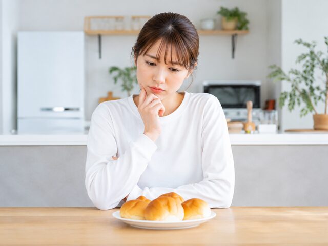 ダイエットを着なしてディナーロールを食べようか悩む女性